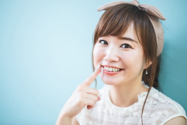 歯を指さして笑う女性