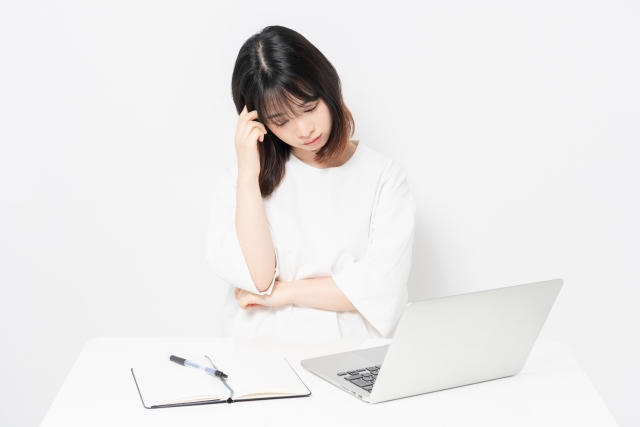 PCを見ながら悩む女性