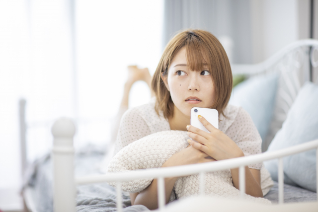 スマホを見て悩む女性
